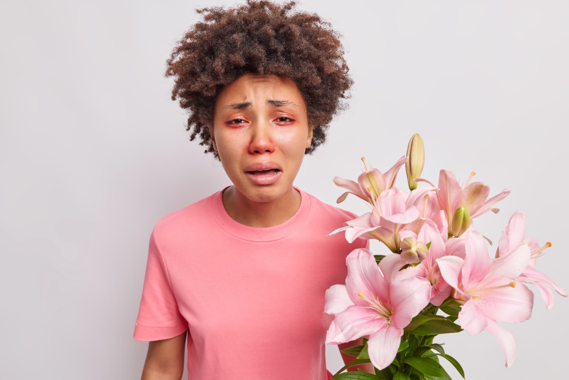 A person experiencing an allergic reaction while holding a bouquet of lilies