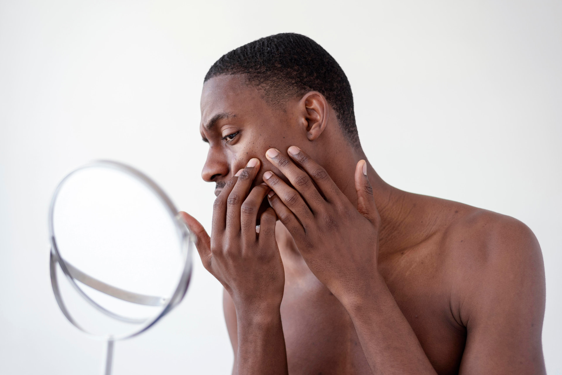 A person examining their face in a mirror for a skin concern