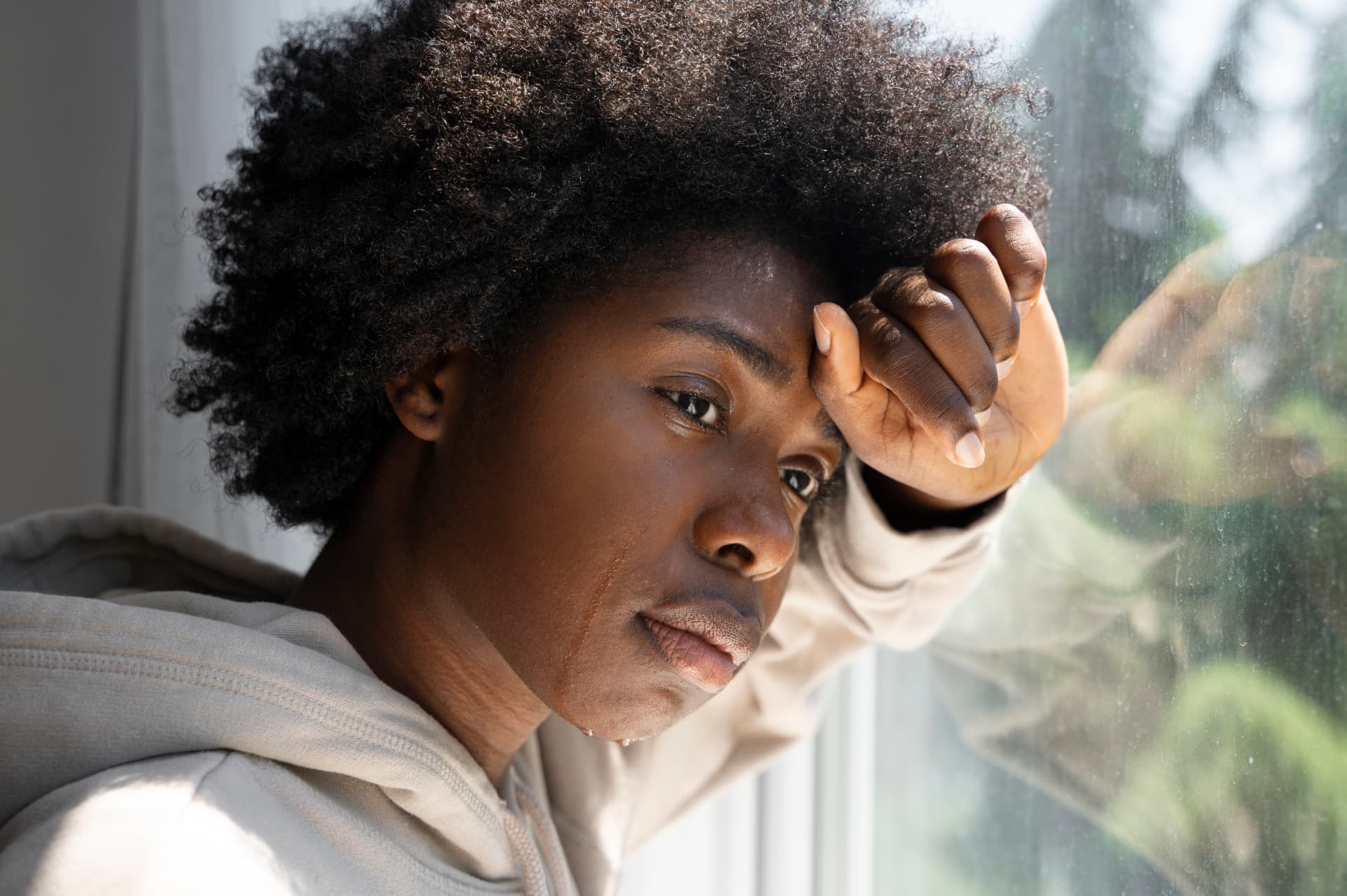 A young person resting by a window in a quiet, reflective moment